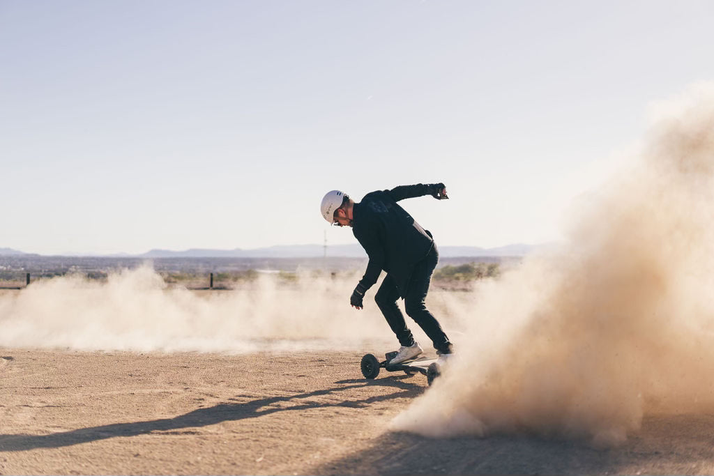 Rider kicking up dust on an ONSRA all-terrain electric skateboard