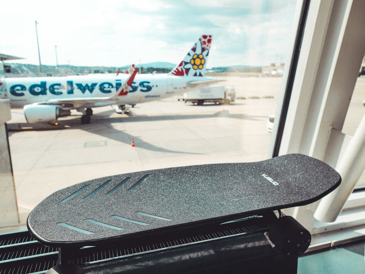ONSRA ZENO on an airport window sill with an Edelweiss airplane behind