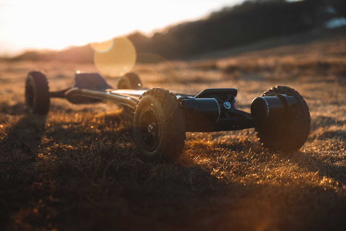 ONSRA VELAR all-terrain electric skateboard on gravel at sunset